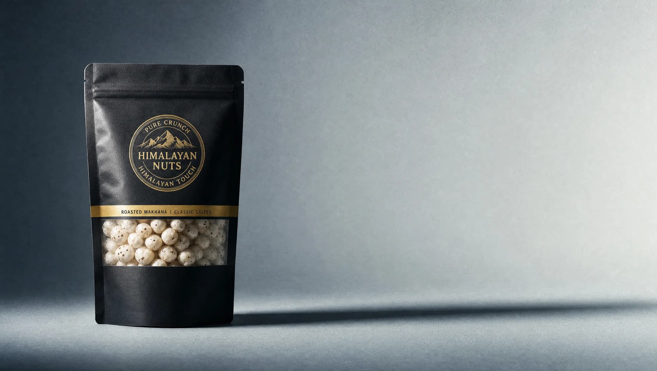 A matte black Himalayan Nuts pouch with a gold seal and a clear window of roasted fox nuts
